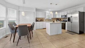 A modern kitchen with white cabinetry, a central island, and stainless steel appliances. - Bright Home w/ Patio + Fenced Yard - Sleeps 8 (Galloway)