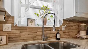A kitchen with a double sink, a potted plant, a dish soap bottle, and a blender. - Bright Home w/ Patio + Fenced Yard - Sleeps 8 (Galloway)