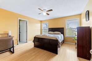 Une chambre à coucher avec un lit, un ventilateur de plafond, une fenêtre et une porte.