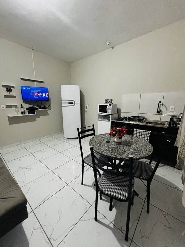 Un espace de vie compact comprenant un coin repas, une cuisine et un téléviseur fixé au mur.