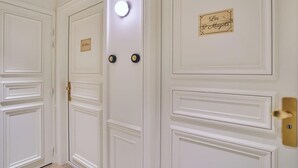 Un ensemble de portes blanches ornées de moulures décoratives et dotées d’une poignée en laiton. On peut y voir deux petites plaques, l’une portant l’inscription « Les Magots » et l’autre « La Plage ».