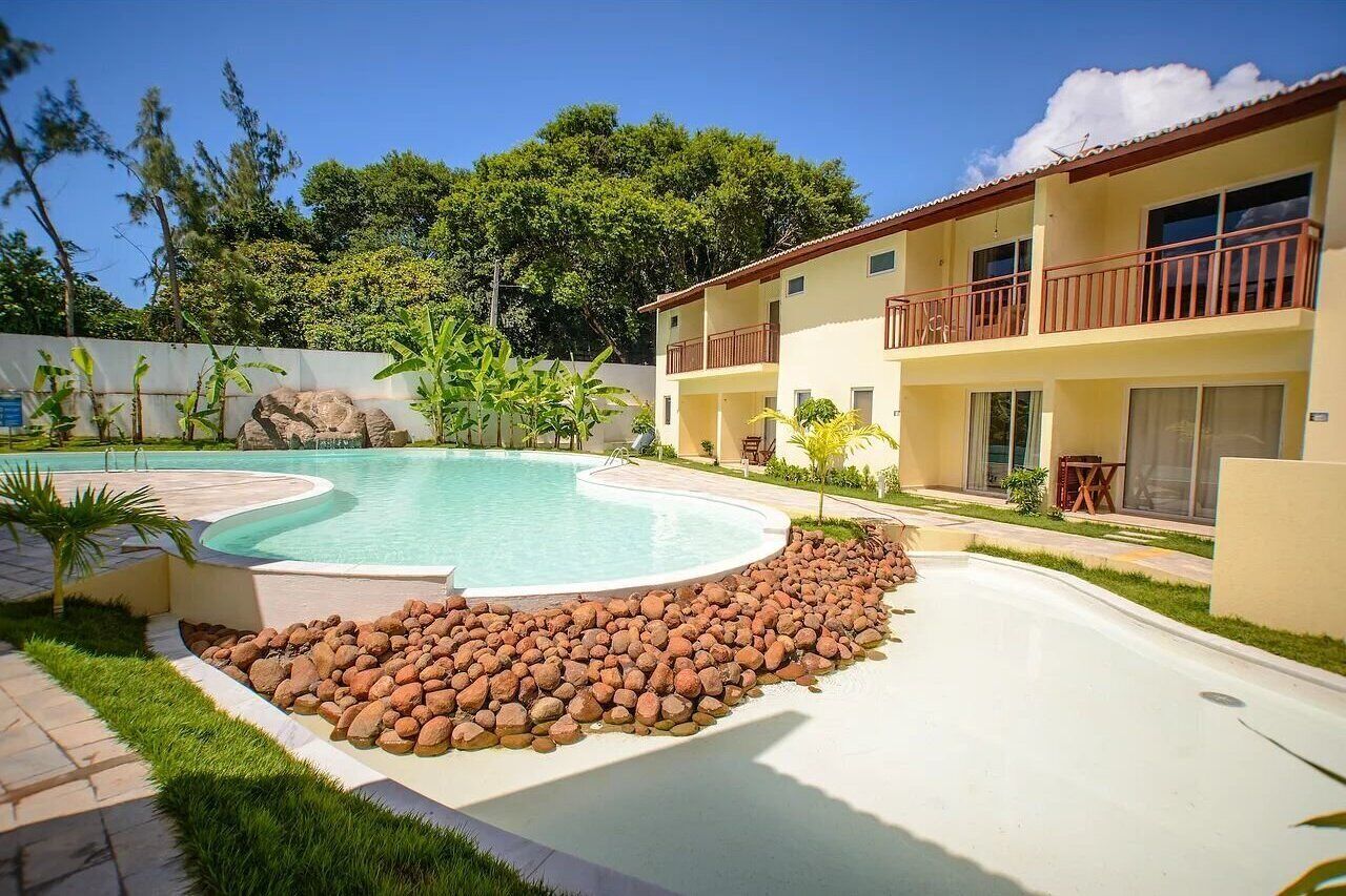 A pool area with a curved design, surrounded by a rock border and greenery.