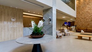 Eine moderne Lobby mit einem Marmortisch, weißen Orchideen und einem Schild mit der Aufschrift 'Beach Class Salvador'.
