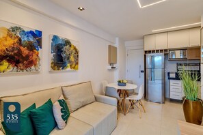 Una sala de estar moderna con un sofá, una mesa de comedor y una zona de cocina con refrigerador.
