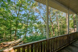 A wooden deck with a view of a forest and a body of water.