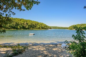 A lake with a dock, surrounded by dense green forest. - Peaceful Waterfront Cottage with Pond Views (Sandwich)