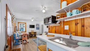 Una cocina compacta con microondas, lavamanos y armarios de madera.