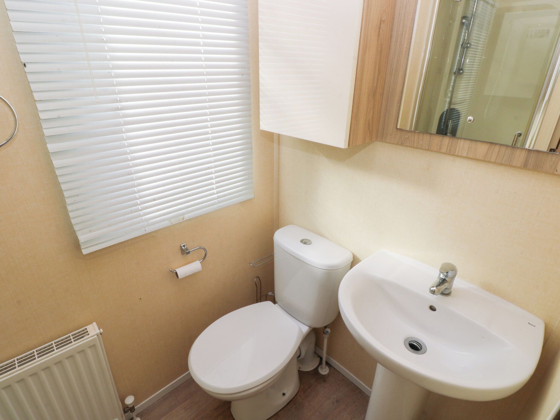 A small bathroom with a toilet, sink, and window blinds.