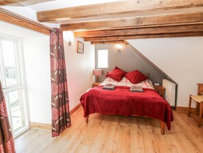 Une chambre avec un plafond en bois, un lit avec une literie rouge, une fenêtre donnant sur un beau paysage et un plancher en bois.