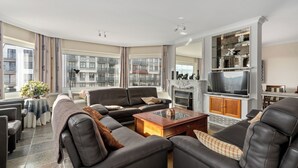 A modern living room with leather sofas, a glass coffee table, and a fireplace.