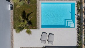An aerial view of a swimming pool with a tiled deck, two lounge chairs, and surrounding palm trees. - The Palms Resort 2BR Villa Dream Three with Pool (Tkon)