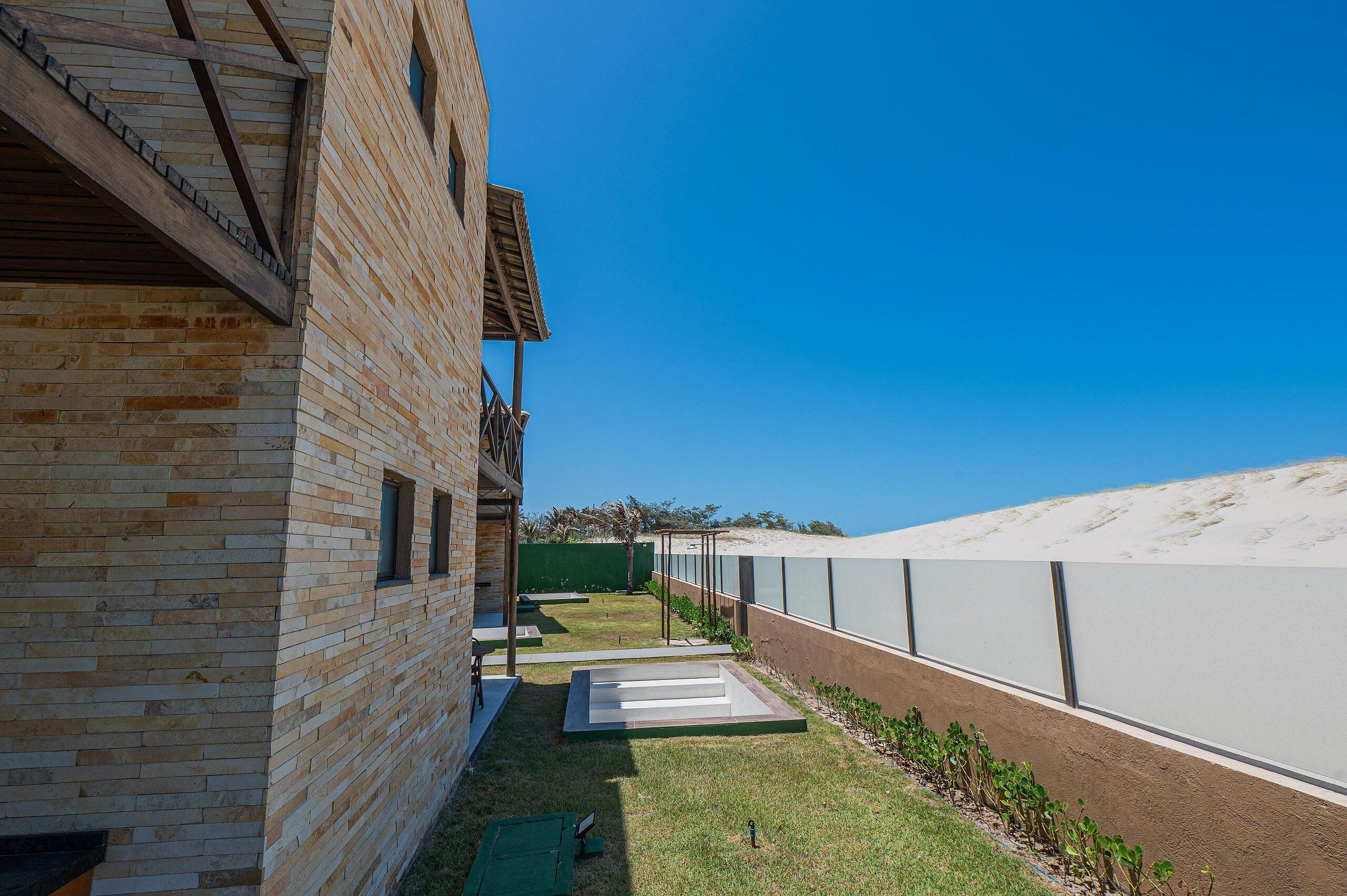 A modern building with a brick facade, a balcony, and a clear blue sky.