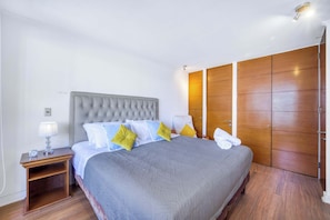 Ein ordentlich eingerichtetes Schlafzimmer mit einem großen Bett, einem Nachttisch mit Lampe und einem Kleiderschrank.