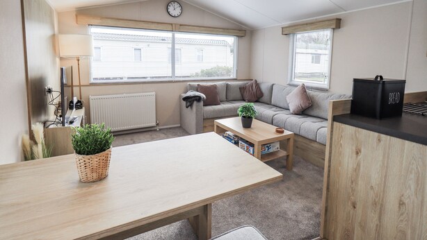 Un espacio acogedor con un sofá, una mesa de centro de madera, un reloj en la pared y un radiador.