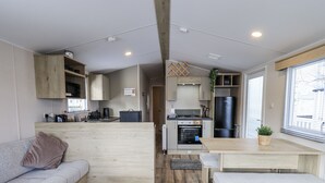 Una cocina moderna con armarios de madera, horno empotrado y refrigerador negro.