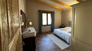 Un dormitorio con cama, mesita de noche, lámpara y ventana con cortinas.