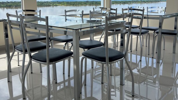 A conference room with a glass table and chairs, large windows with a view of a lake and greenery.