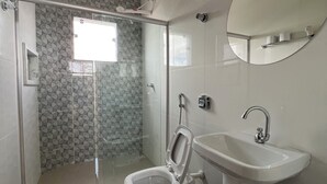 A modern bathroom with a glass-enclosed shower, a toilet, and a sink.