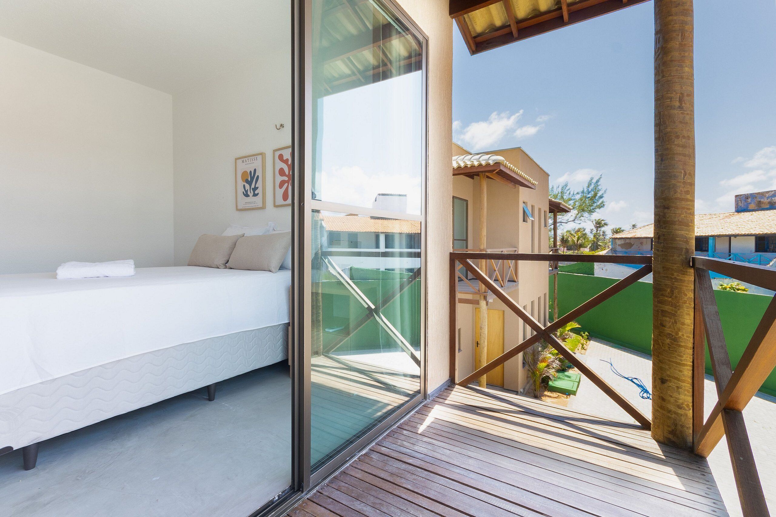 A bedroom with a bed, a glass wall, and a view of the outside.