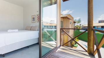 A bedroom with a bed, a glass wall, and a view of the outside.