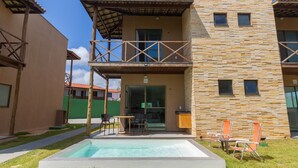 Ein zweistöckiges Gebäude mit Swimmingpool, Außenbereich zum Sitzen und einer überdachten Terrasse.