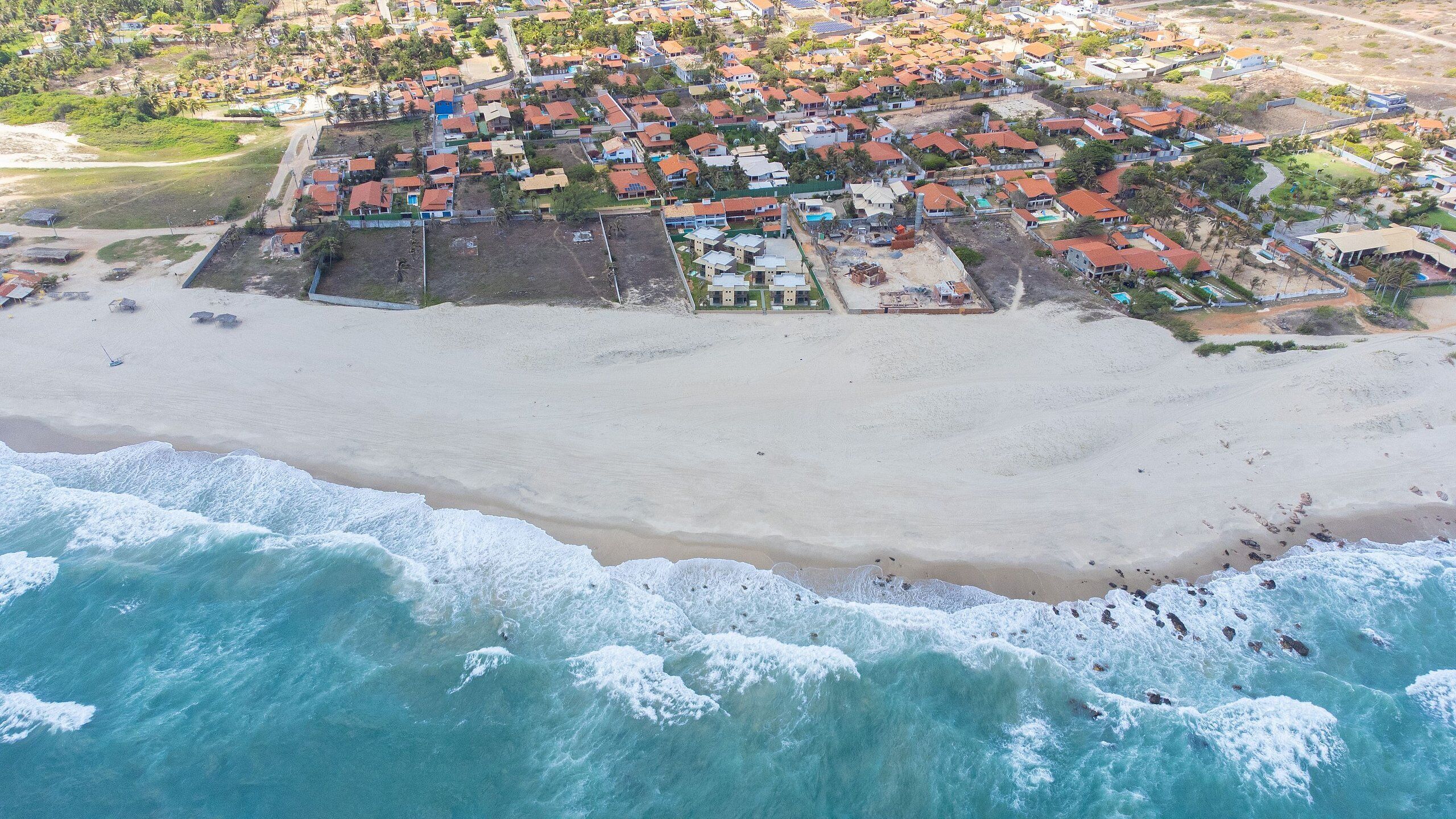 An aerial view of a coastal town with a sandy beach and ocean waves.