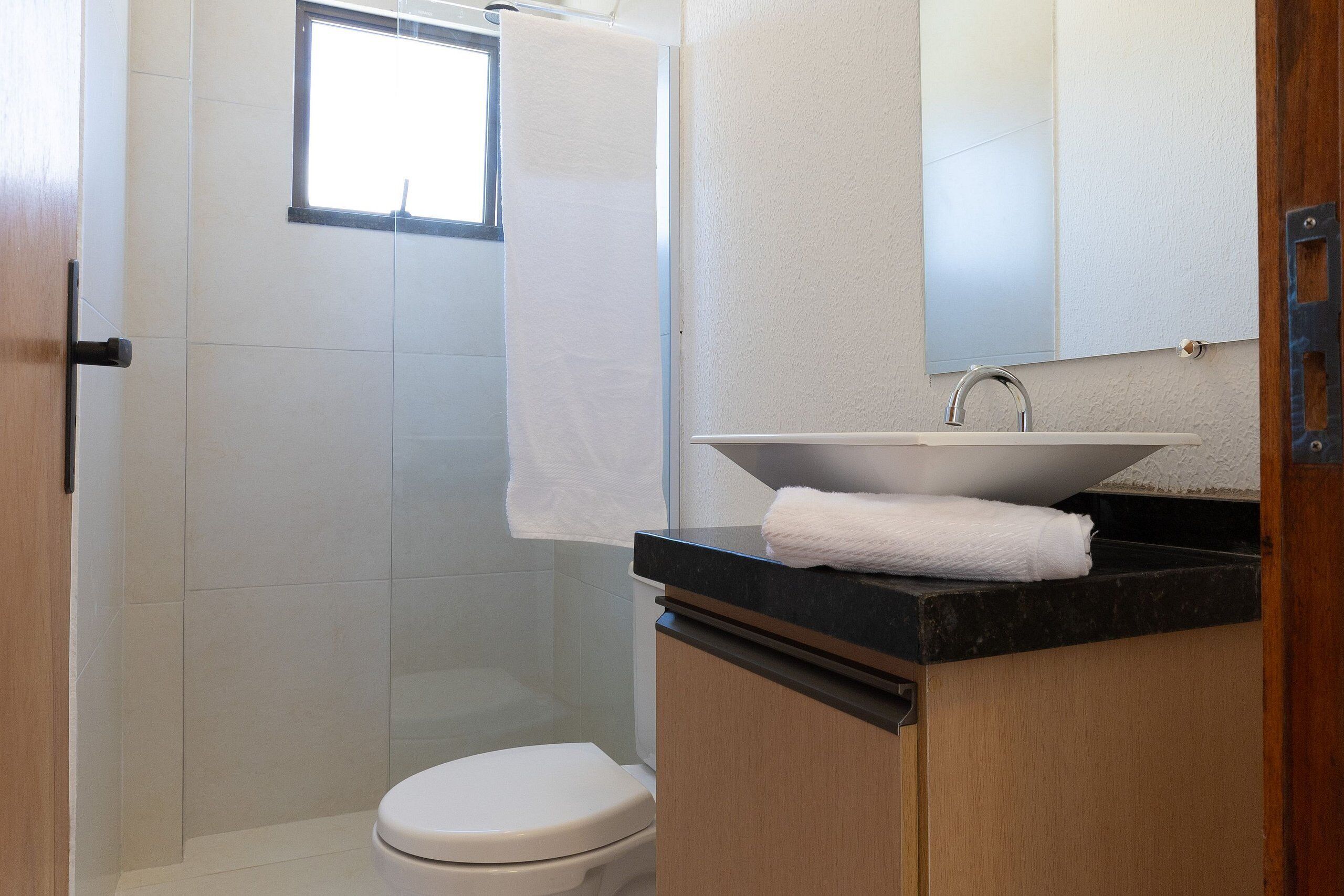 A bathroom with a toilet, a sink with a mirror above it, and a shower area.