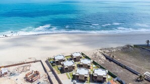 Ein Küstenhotel mit mehreren Gebäuden, einem Sandstrand und dem Meer im Hintergrund.