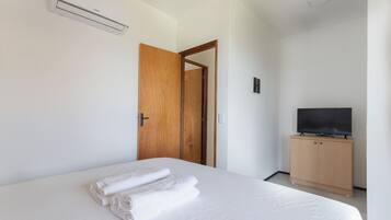 Una habitación de hotel con una cama, un armario de madera, un televisor y un equipo de aire acondicionado.