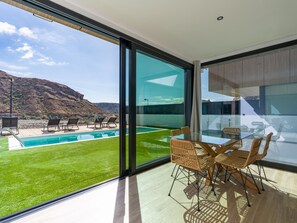 Un interior moderno con una pared de vidrio que da a una piscina y un paisaje montañoso.