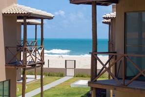 Une propriété située en bord de mer, dotée d’un espace extérieur couvert, d’un chemin menant à la plage et offrant une vue sur l’océan.