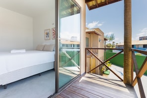 A bedroom with a bed, a glass wall, and a view of the outside. - Beachfront Duplex #A6 - Aquiraz By Carpediem (Aquiraz)