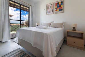 A bedroom with a bed, a nightstand, a window with curtains, and artwork on the wall. - Beachfront Duplex #A6 - Aquiraz By Carpediem (Aquiraz)