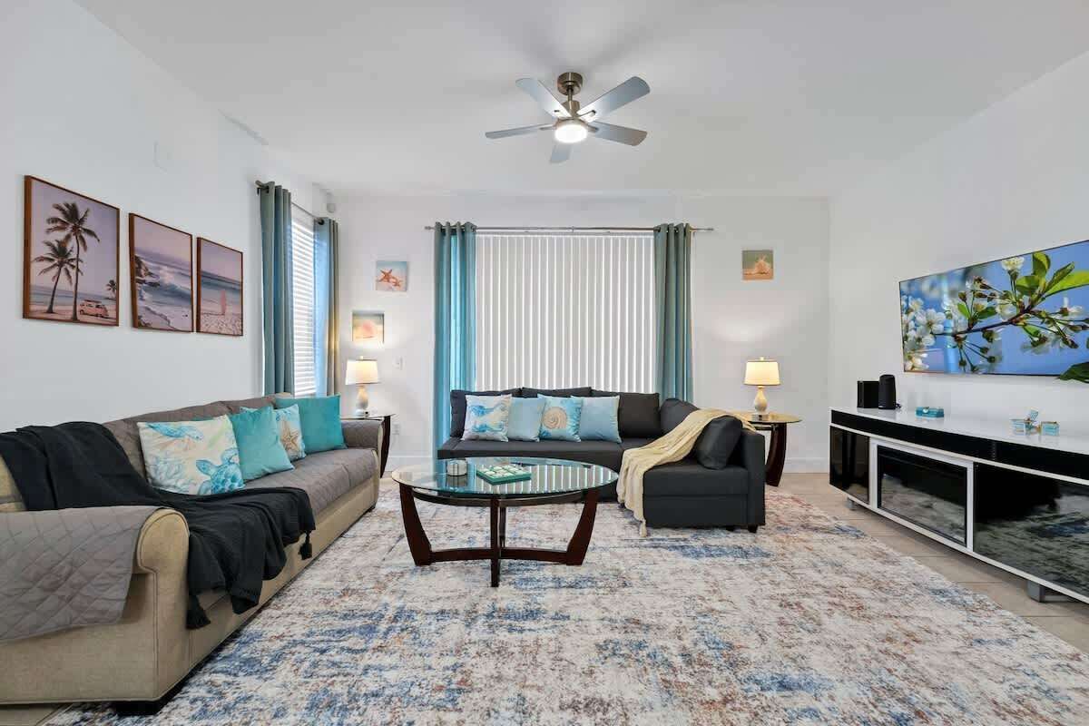 A living room with a sofa, armchairs, a coffee table, a TV, and a ceiling fan.