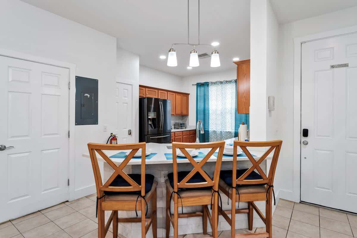Une cuisine moderne avec des meubles en bois, un îlot central doté de chaises et un luminaire suspendu.