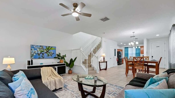 A spacious living room with a sofa, coffee table, and a staircase leading to the upper floor. - Family Getaway Near Disney - 3BR and Pool Access (Kissimmee)