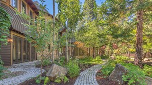 A stone pathway leading to a wooden house with a garden. - Tewesi Manor | Historic Tahoe Lakefront w/ Private Pier (Carnelian Bay)