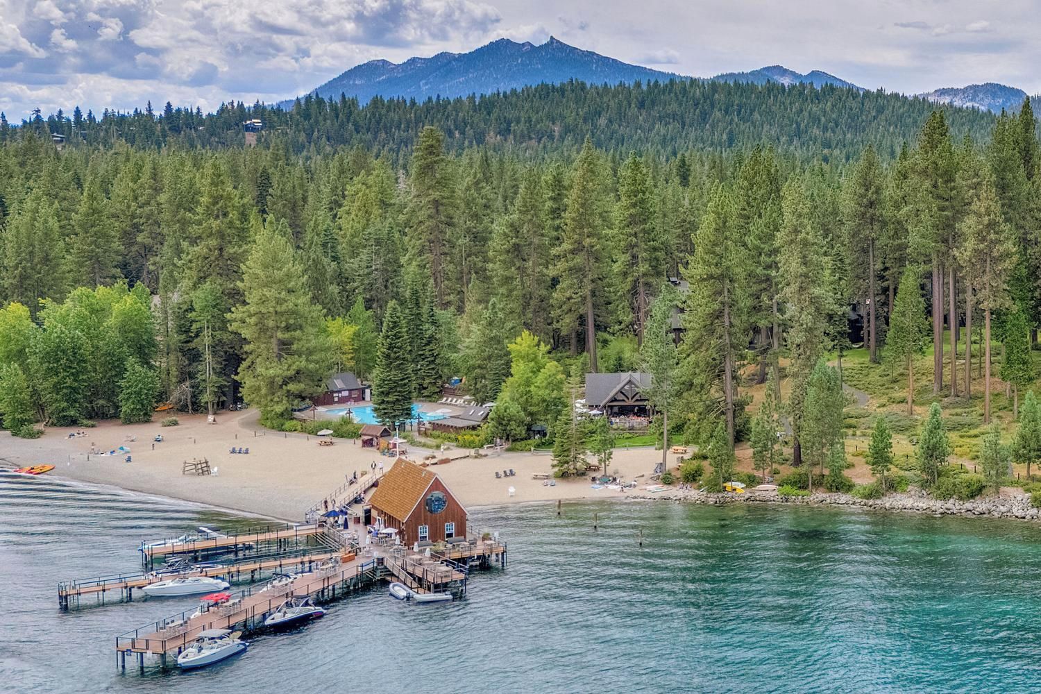 A lakeside property with a dock, boats, and a building with a large window overlooking the water.