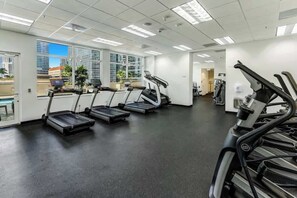 Un gimnasio con cintas de correr, bicicletas estáticas y un amplio ventanal con vistas a la ciudad.