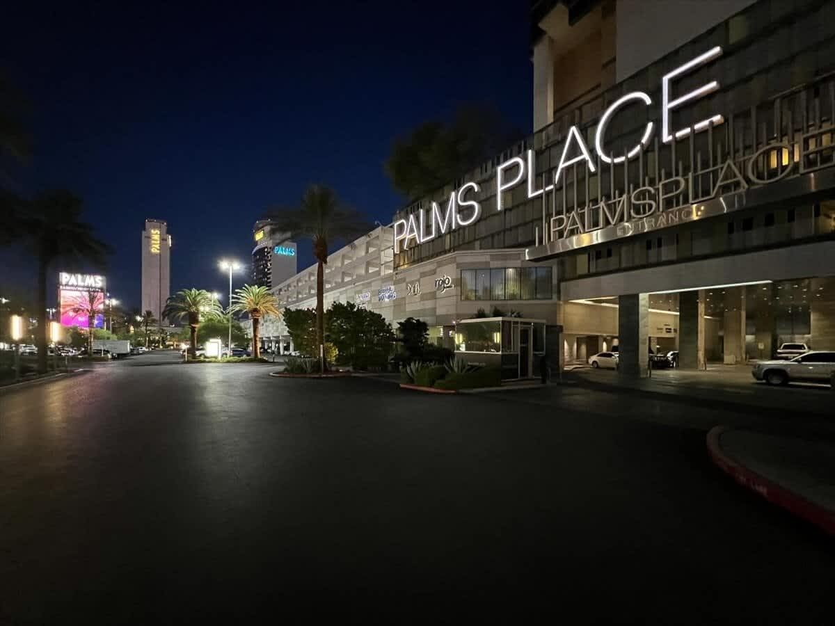 A hotel entrance with a large illuminated sign reading "PALMS PLACE."