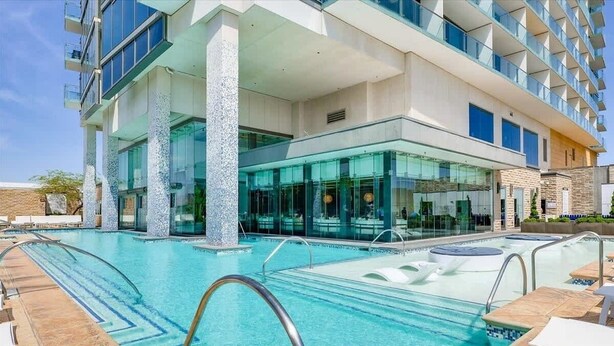Ein modernes Hotel mit großem Außenpool, mehreren Balkonen und einer Glasfassade.