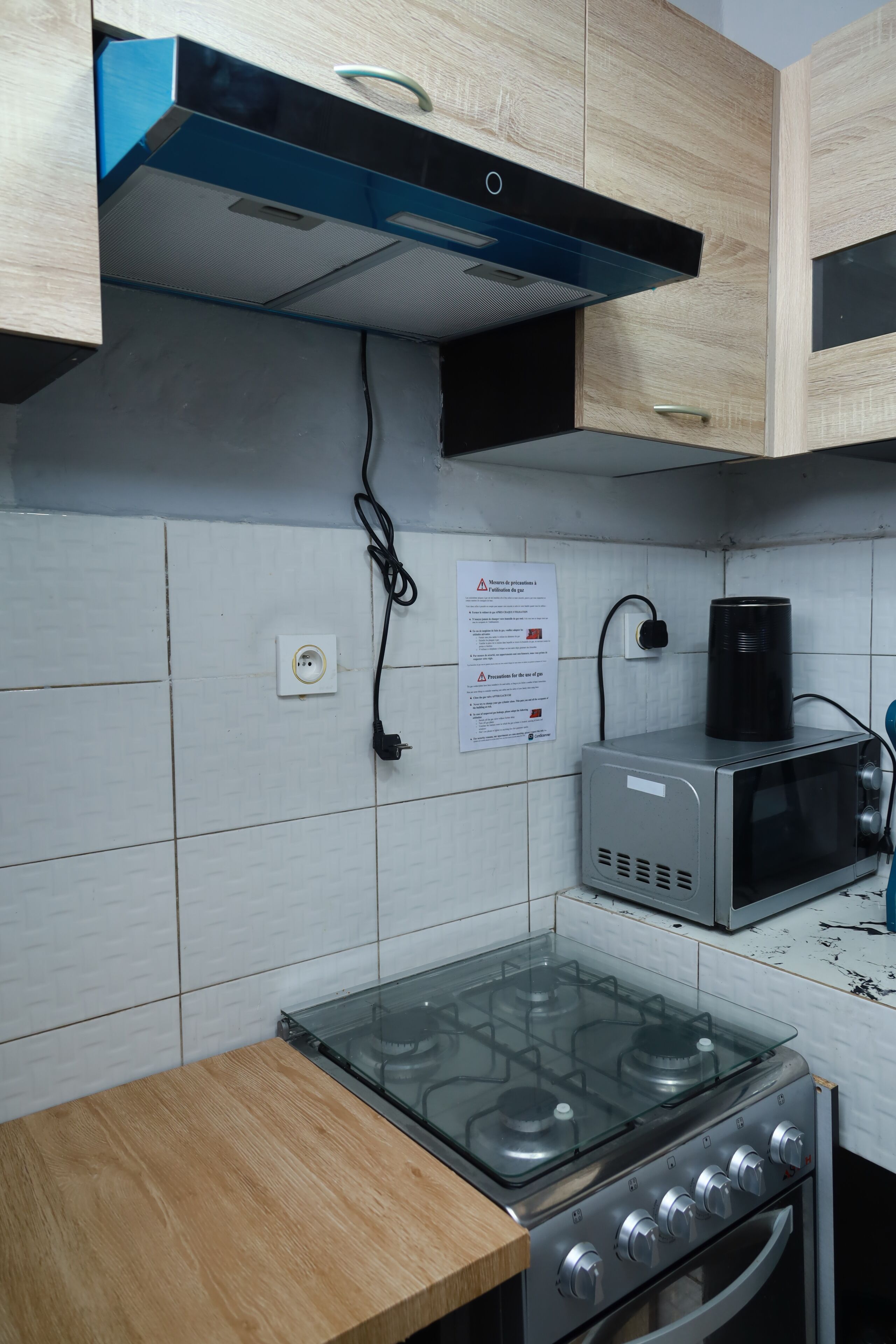 A kitchen with a gas stove, a microwave, and a blue range hood.