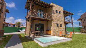 A two-story building with a balcony, a swimming pool, and outdoor seating. - Beachfront Duplex #a10 in Barro Preto by Carpediem (Aquiraz)