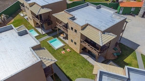 Un immeuble à plusieurs étages doté d’une piscine sur le toit, d’un espace extérieur aménagé et d’un escalier menant à un balcon.