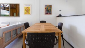 A dining area with a wooden table and black chairs, a sofa, and two paintings on the wall. - Beachfront Duplex #a10 in Barro Preto by Carpediem (Aquiraz)