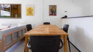 Uma sala de jantar com uma mesa de madeira e cadeiras pretas, um sofá e duas pinturas na parede.