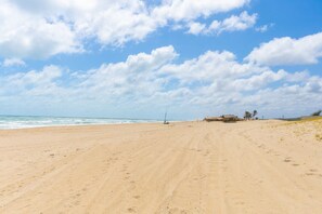 Ein weiter Sandstrand mit Fußabdrücken, die zum Meer führen.