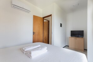 Une chambre d’hôtel équipée d’un lit, d’une armoire en bois, d’une télévision et d’un appareil de climatisation.