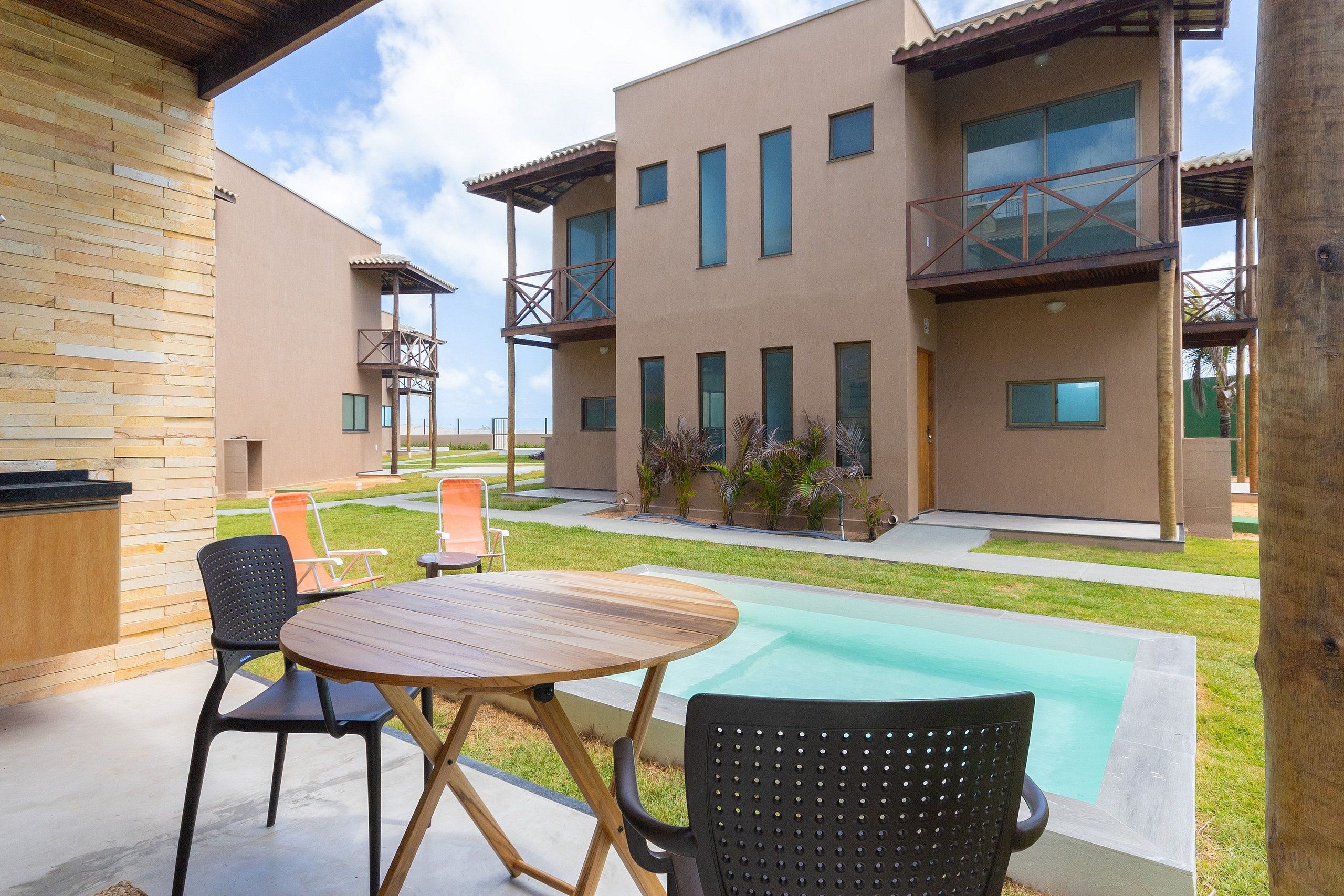 A modern outdoor area with a pool, a wooden table, and chairs.