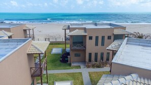 Une propriété située en bord de mer, comprenant plusieurs bâtiments, une cour verdoyante et offrant une vue sur l’océan.